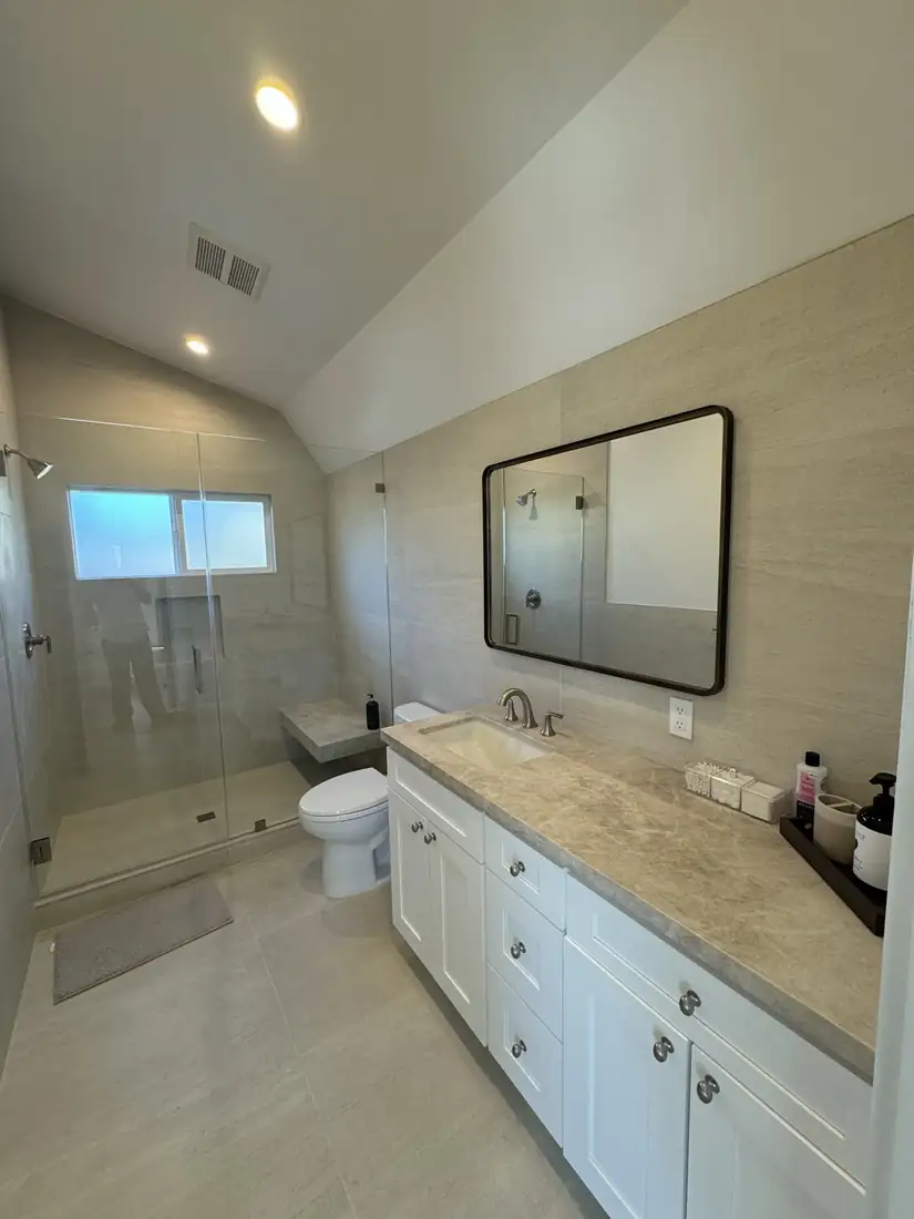 Primary bathroom with porcelain slab walls and floating stone bench